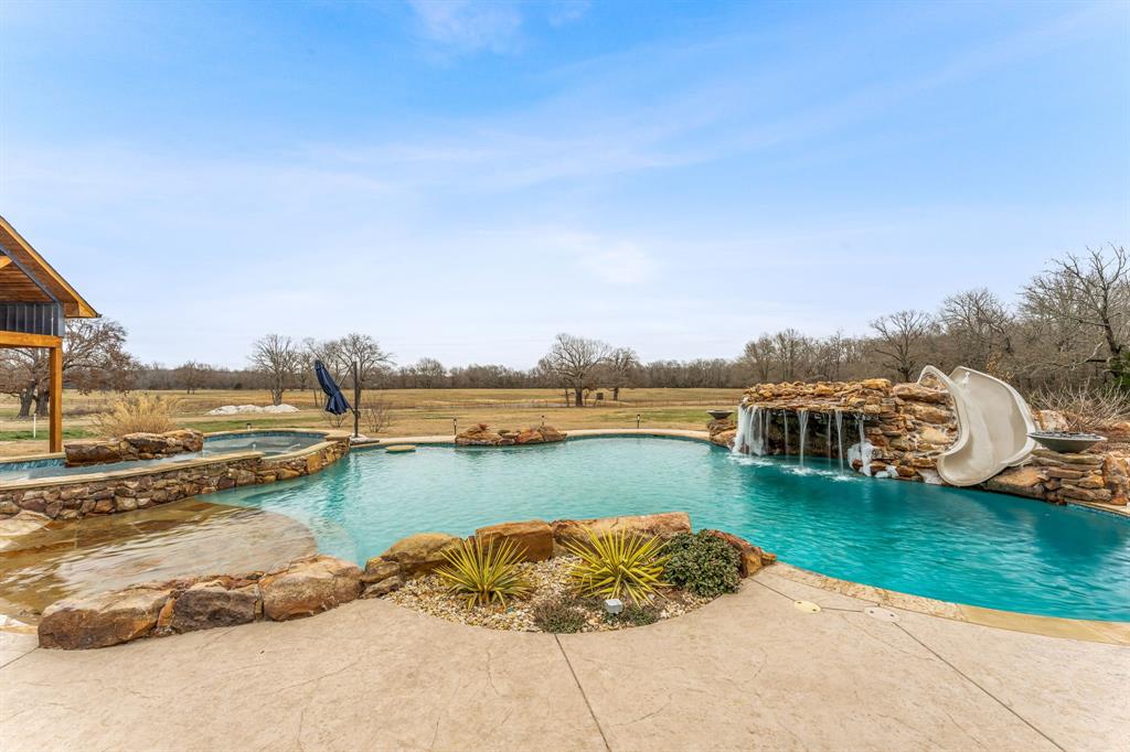 239 32507th Road Paris, TX 75460 - Photo 26 of 40 View of pool featuring a patio area, a water slide, and a pool with connected hot tub
