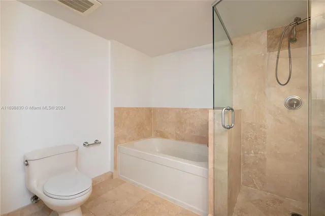 a bathroom with a granite countertop bathtub shower and toilet