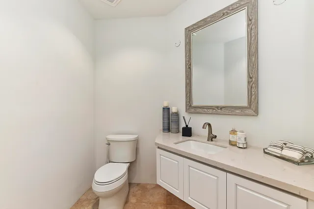 a bathroom with a granite countertop toilet sink mirror and vanity