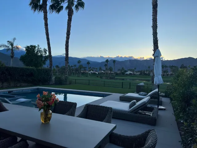a view of a chairs and table in patio and yard