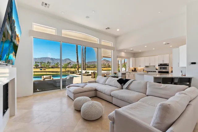 a living room with furniture kitchen view and a large window