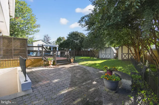 a patio with table and chairs and potted plants with wooden floor and fence