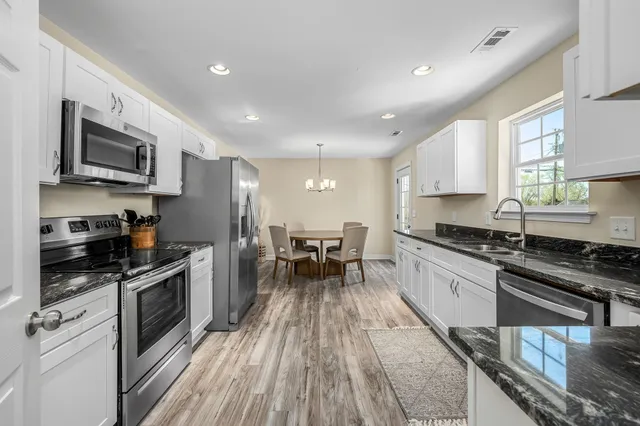 a kitchen with granite countertop a stove top oven a sink dishwasher a dining table and chairs with wooden floor