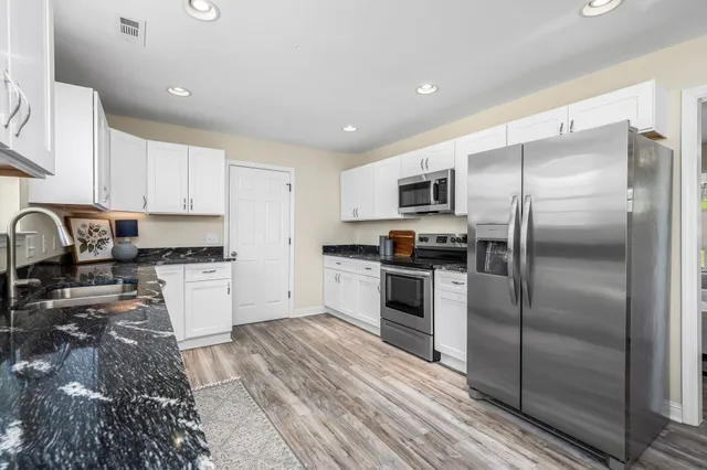 a kitchen with granite countertop a refrigerator and a stove top oven