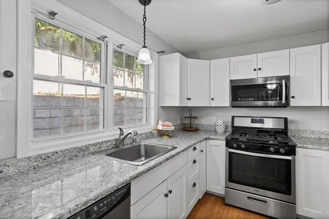 a kitchen with granite countertop a sink stainless steel appliances and cabinets
