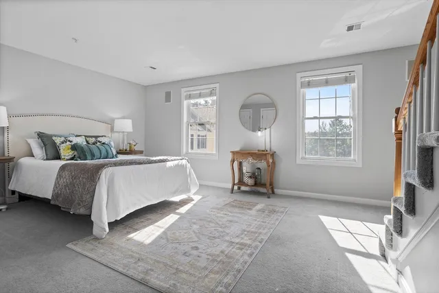 a spacious bedroom with a bed a mirror and a large window