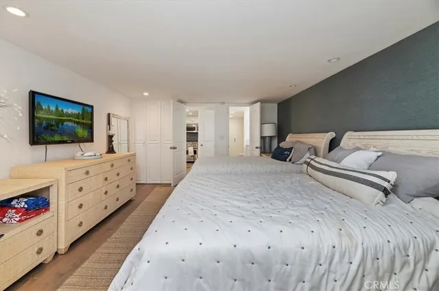 a spacious bedroom with a large bed and a flat tv screen on dresser