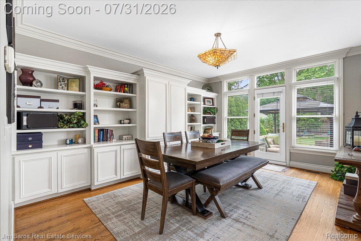 637 Washington Road Grosse Pointe, MI 48230 - Photo 11 of 40 Dining space with hardwood flooring, extensive built-in cabinetry, crown molding, and large windows with a glass-paneled door