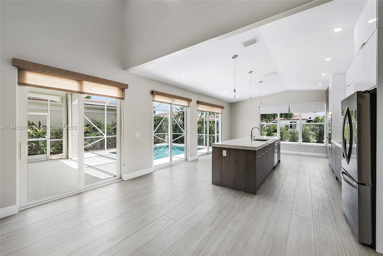 3670 Northwind Court Jupiter, FL 33477 - Photo 12 of 45 a large kitchen with a large window a refrigerator and a wooden floor