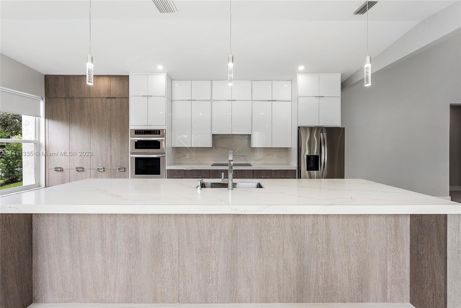 3670 Northwind Court Jupiter, FL 33477 - Photo 7 of 45 a large kitchen with stainless steel appliances kitchen island a large counter top a sink and a refrigerator