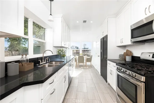 a kitchen with stainless steel appliances granite countertop a sink a stove and a refrigerator