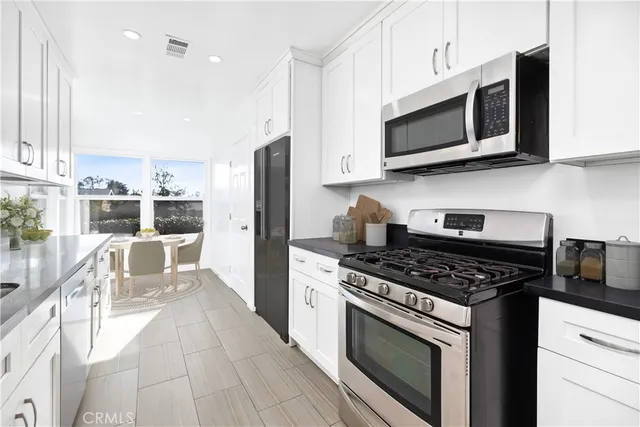 a kitchen with stainless steel appliances granite countertop a stove a microwave a sink a refrigerator and cabinets