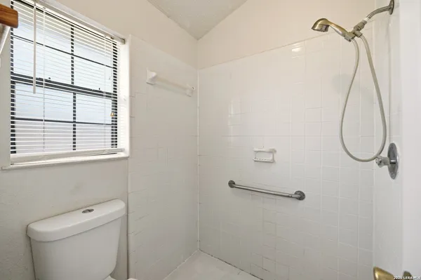 a bathroom with a shower a toilet and a window