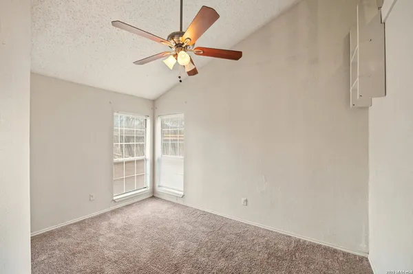 an empty room with windows and fan