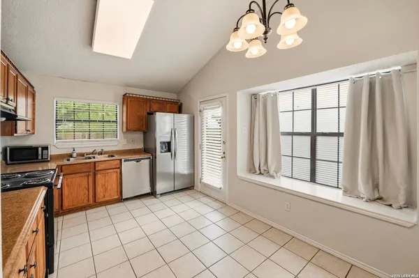a kitchen with granite countertop a stove a sink dishwasher a dining table and chairs with wooden floor