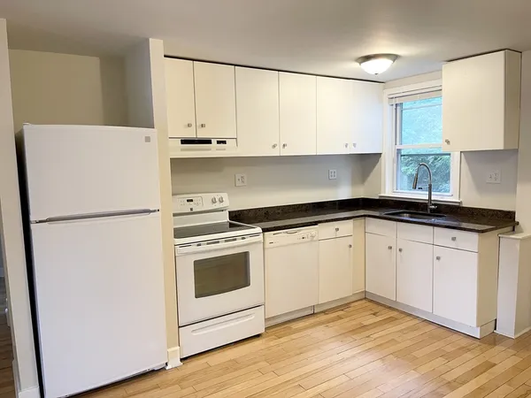 a kitchen with granite countertop white cabinets and white appliances