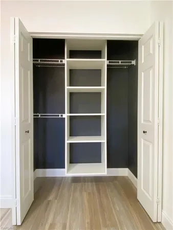 a view of an empty room with wooden floor and closet