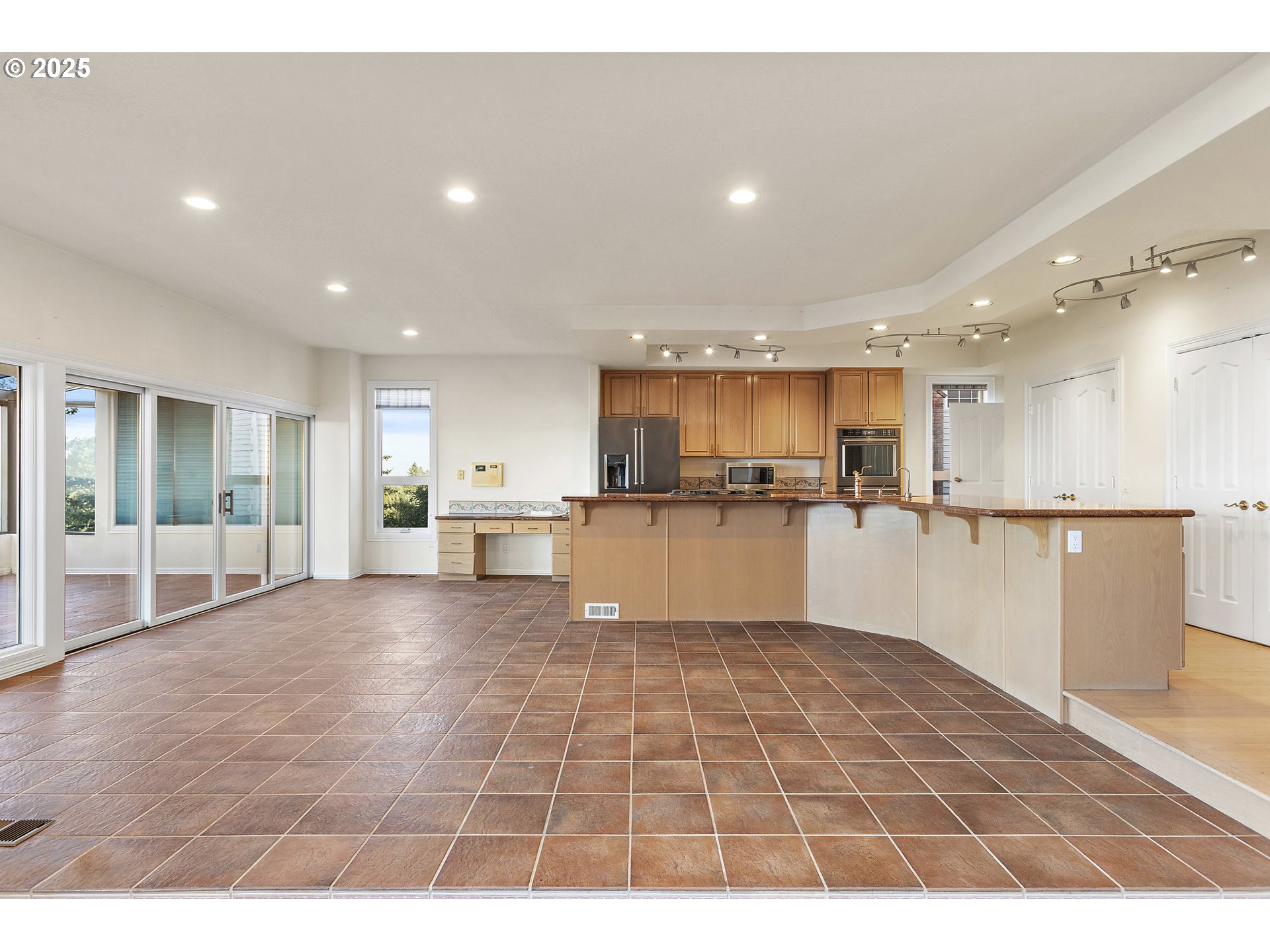 9101 Northeast Cliff Street Portland, OR 97220 - Photo 12 of 26 a open kitchen with stainless steel appliances granite countertop a refrigerator a sink a stove and white cabinets with wooden floor