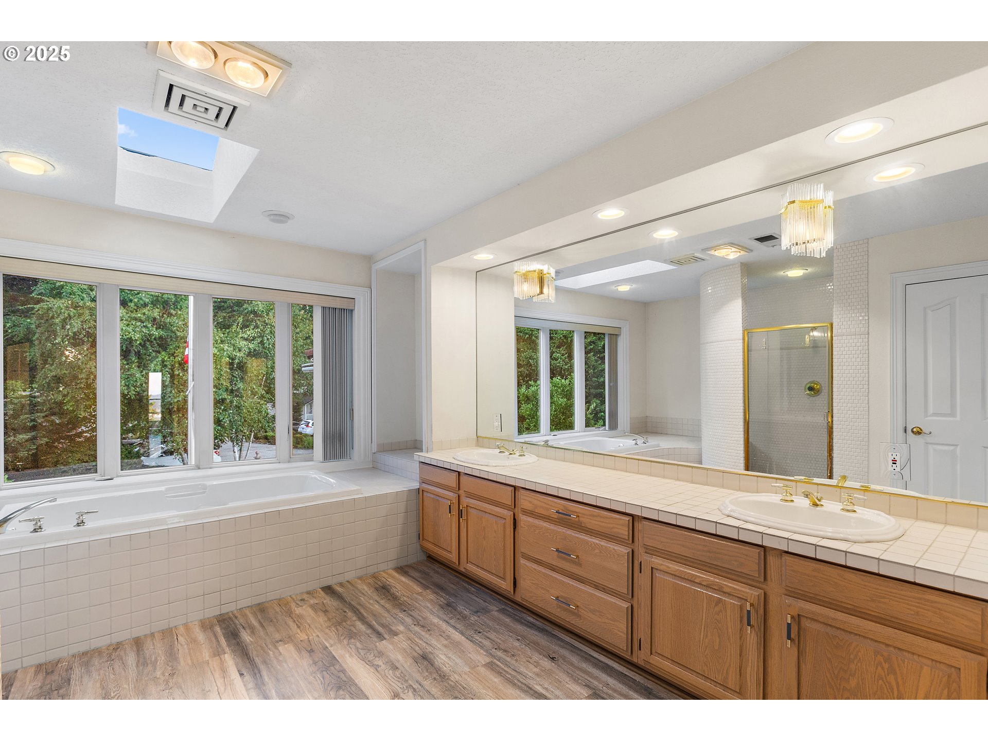 9101 Northeast Cliff Street Portland, OR 97220 - Photo 23 of 26 a bathroom with a sink large mirror a bathtub and next to a window