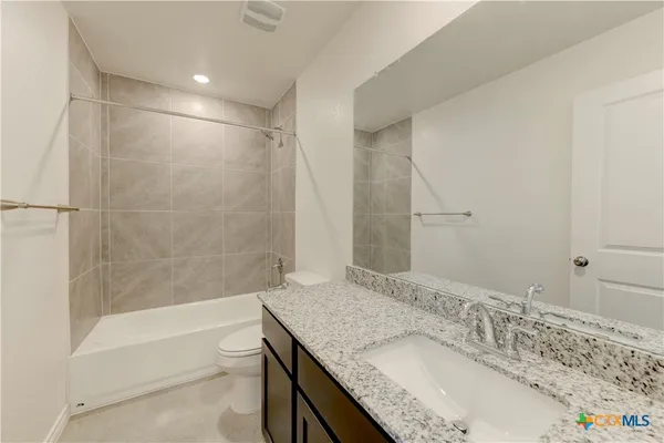a bathroom with a granite countertop sink a toilet and bathtub