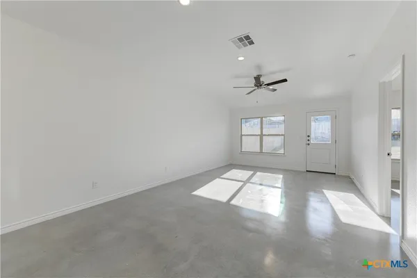 an empty room with windows and ceiling fan