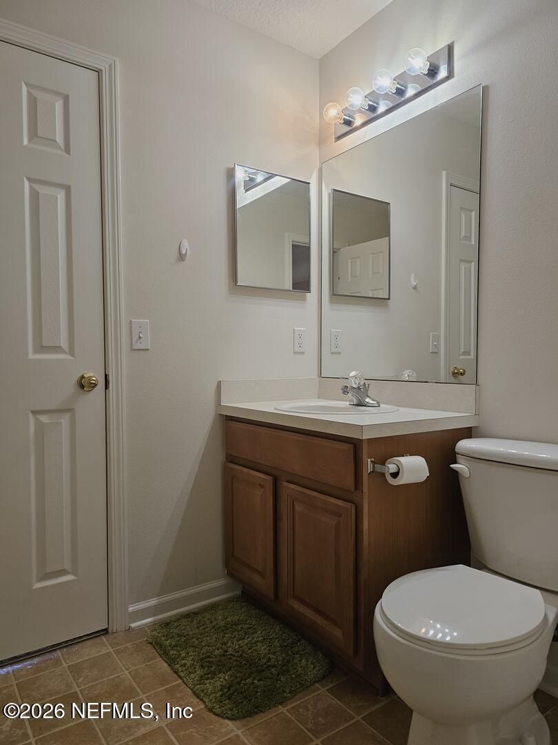 7826 Melvin Road Jacksonville, FL 32210 - Photo 10 of 17 a bathroom with a granite countertop toilet sink and mirror