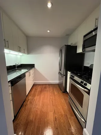 a kitchen with granite countertop a refrigerator and a stove top oven