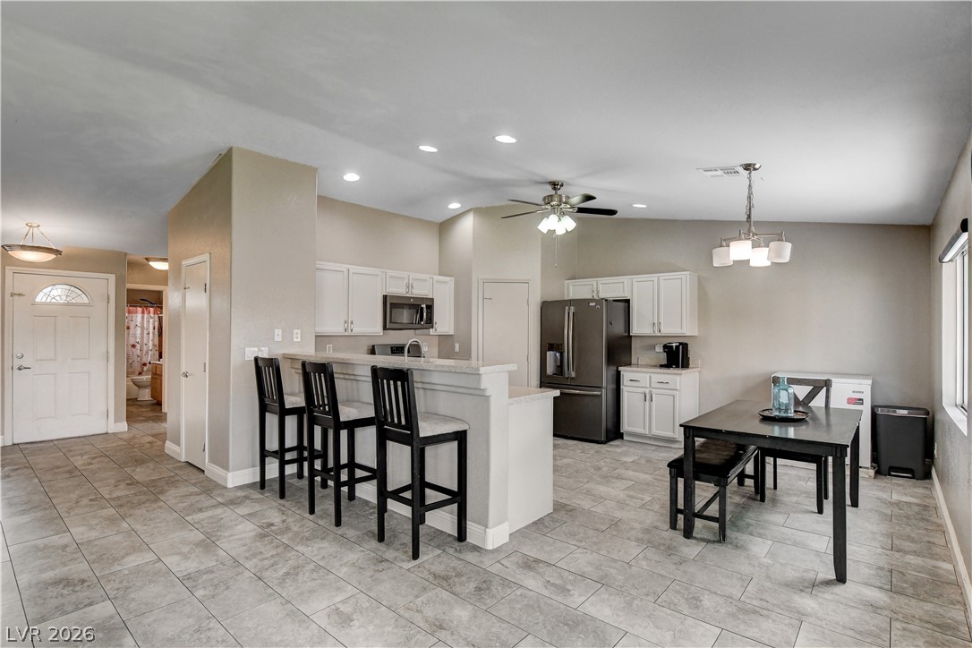 910 Cobblestone Cove Road North Las Vegas, NV 89081 - Photo 7 of 30 An open-concept living area features a breakfast bar, ample cabinetry, and a dining space with a view.