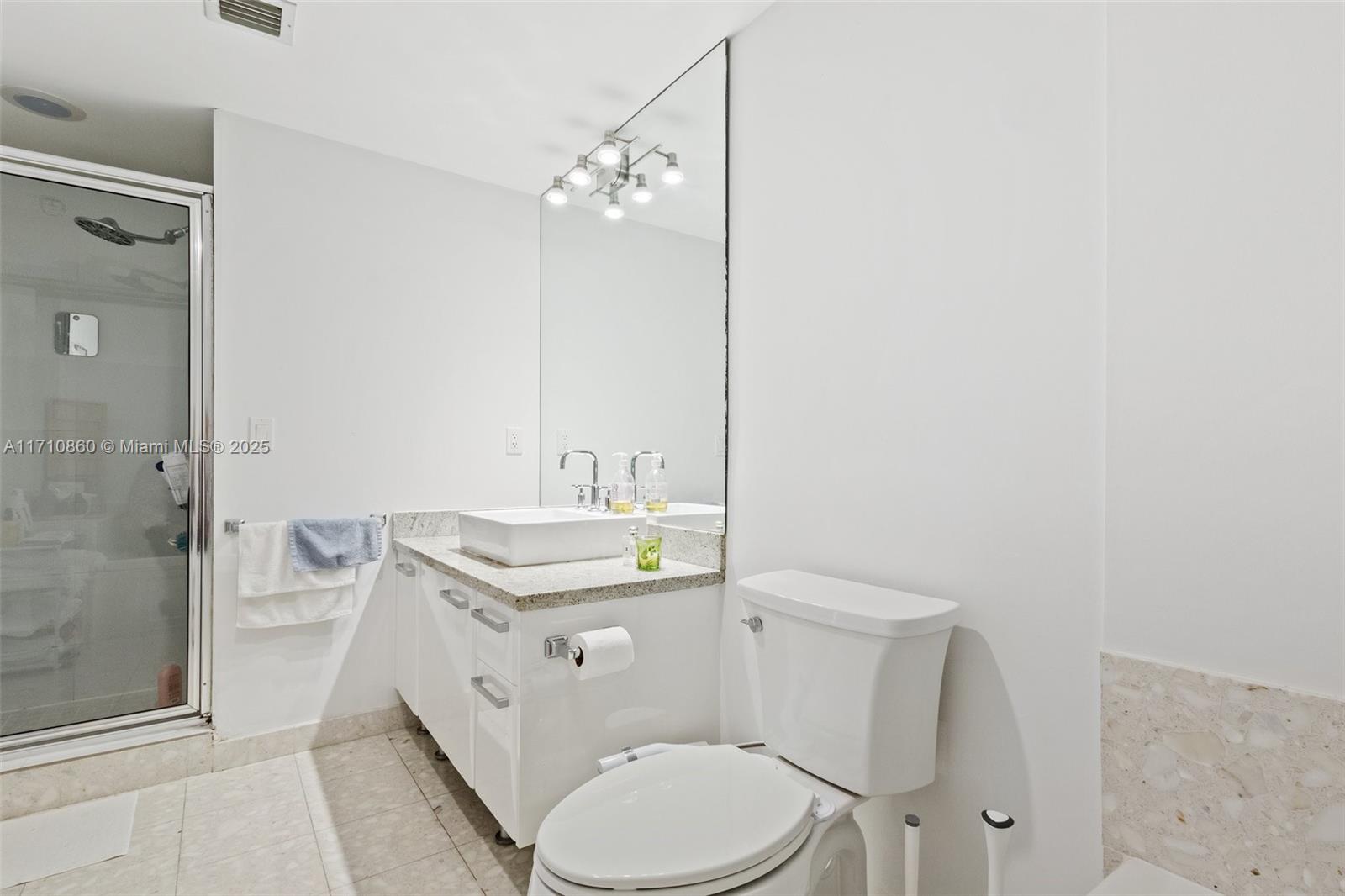 185 Southwest 7th Street, Unit 3111 Miami, FL 33130 - Photo 22 of 40 a bathroom with a granite countertop sink toilet a mirror and shower