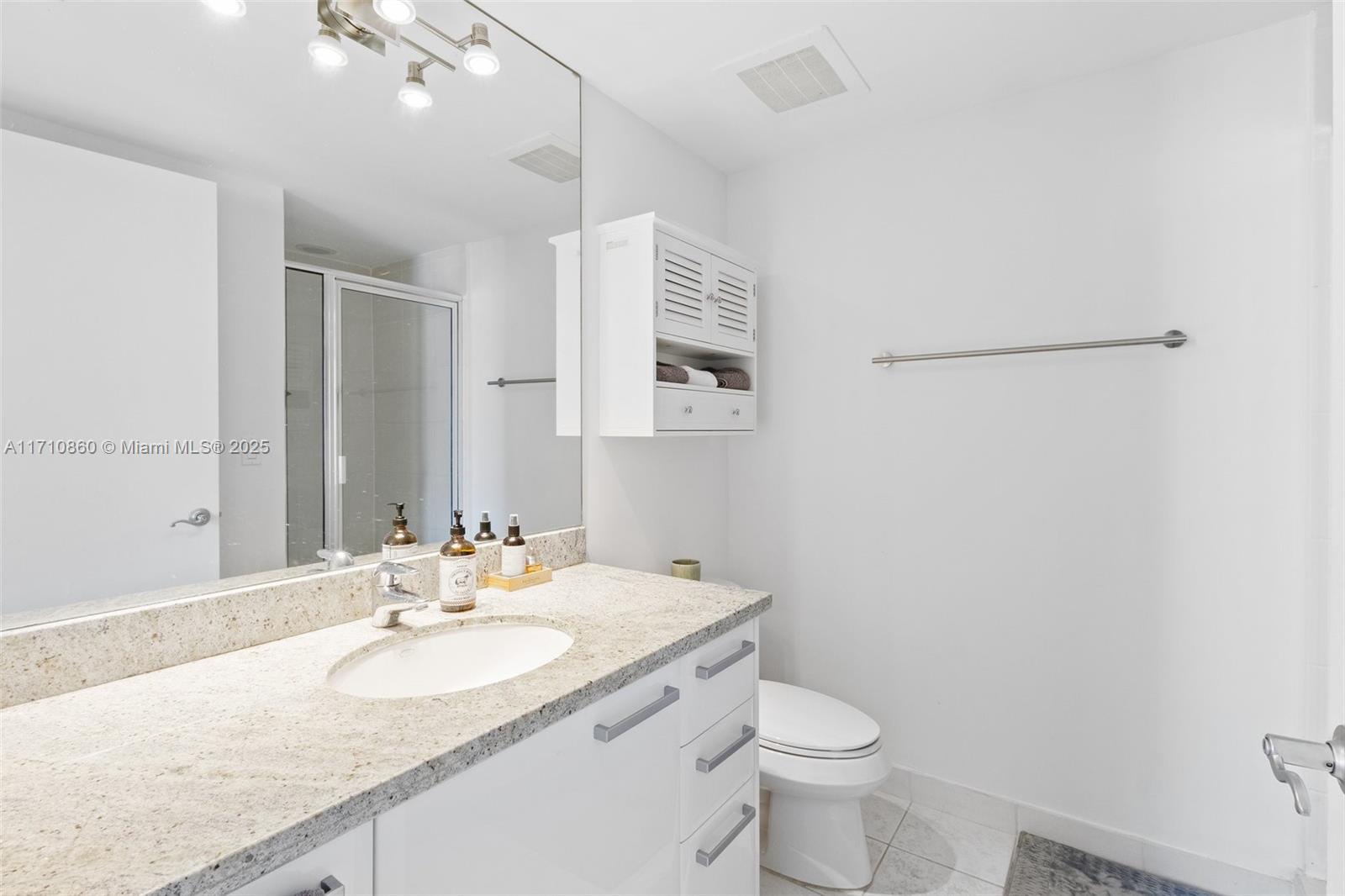 185 Southwest 7th Street, Unit 3111 Miami, FL 33130 - Photo 24 of 40 a bathroom with a granite countertop sink a toilet and a mirror