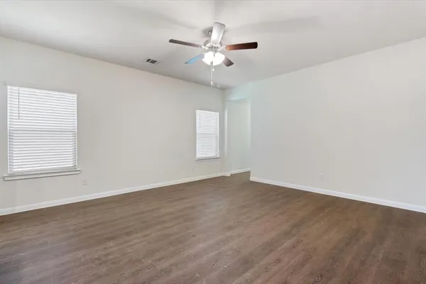 an empty room with wooden floor and ceiling fan