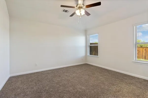 an empty room with windows and fan