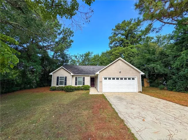 a view of a house with a yard and large trees