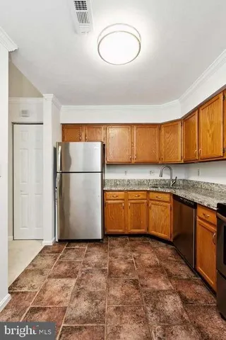 a kitchen with granite countertop a refrigerator and a stove top oven