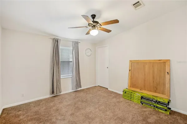 a view of an empty room with chandelier fan