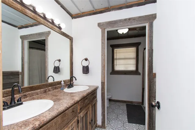 a bathroom with a granite countertop sink a toilet and mirror