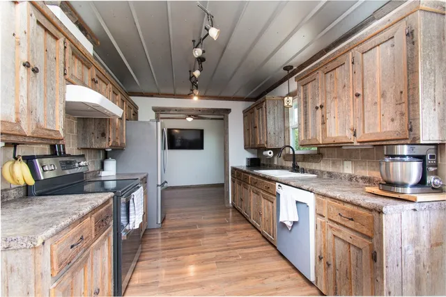 a kitchen with stainless steel appliances granite countertop a sink a stove and a refrigerator