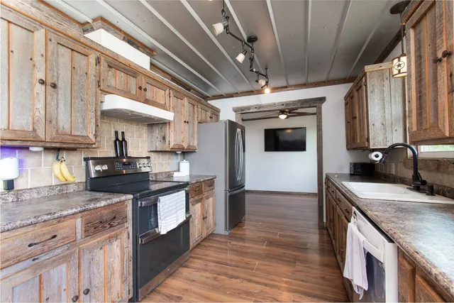 a kitchen with stainless steel appliances granite countertop a sink a stove and cabinets