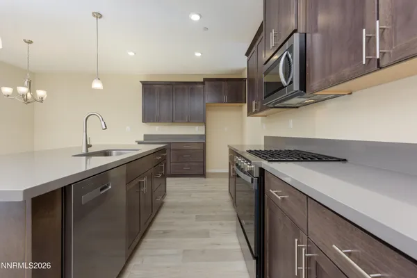 a kitchen with stainless steel appliances granite countertop a sink a stove and a wooden floors