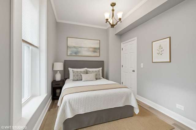 642 East 90th Street Chicago, IL 60619 - Photo 7 of 13 a bedroom with a large bed and a chandelier