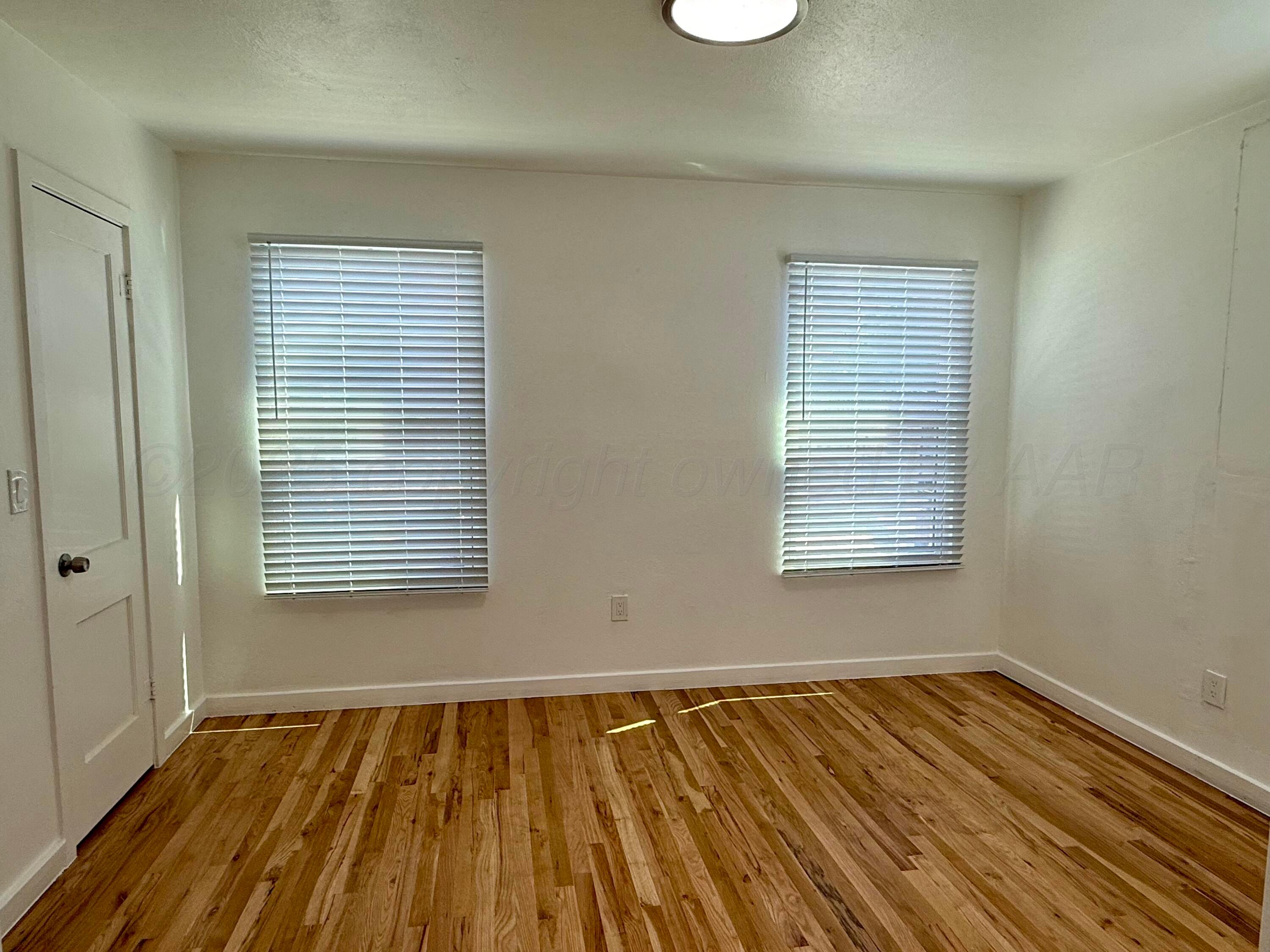1303 Boyd Street Borger, TX 79007 - Photo 14 of 19 a view of an empty room with wooden floor and a window