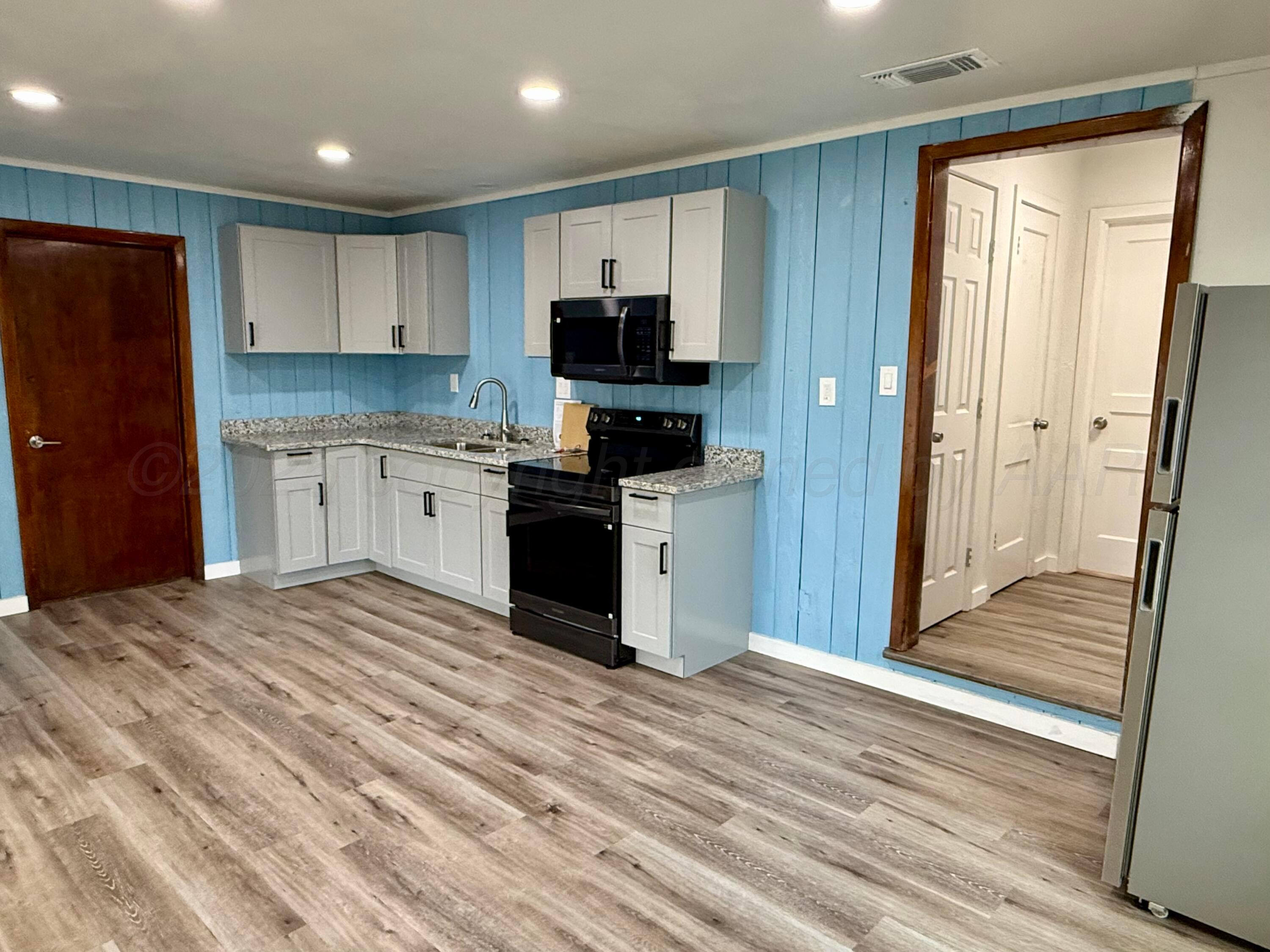 1303 Boyd Street Borger, TX 79007 - Photo 5 of 19 a kitchen with granite countertop a refrigerator and a sink