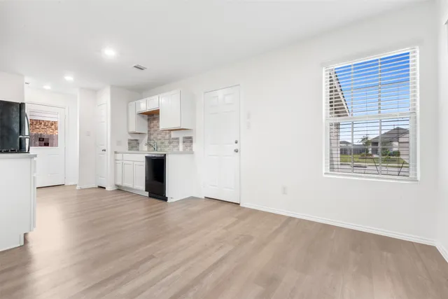 a kitchen with stainless steel appliances a stove top oven a sink a refrigerator white cabinets and wooden floor