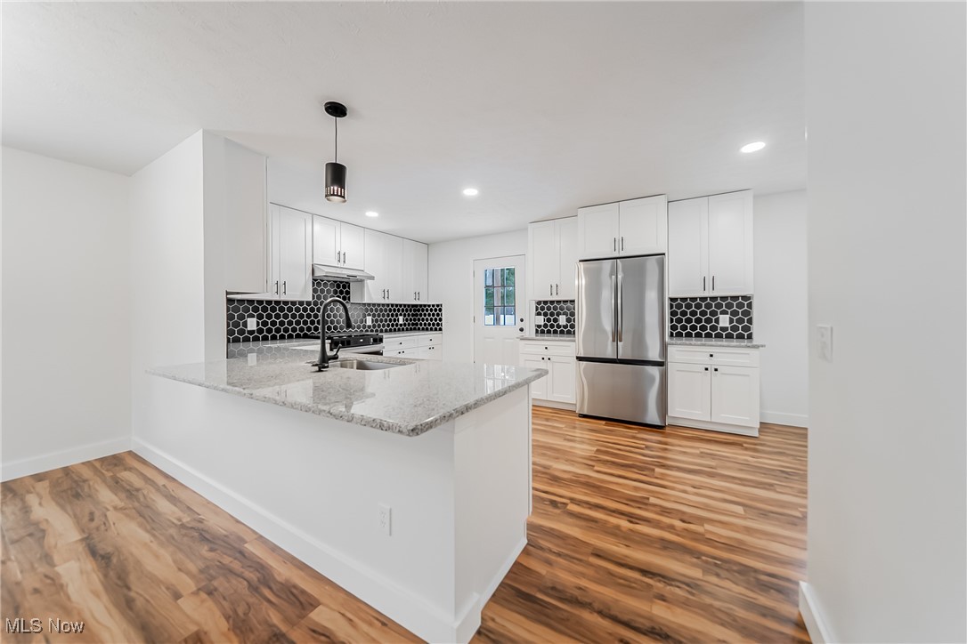7488 Greenwich Road Seville, OH 44273 - Photo 5 of 37 Kitchen featuring white cabinets, freestanding refrigerator, light stone counters, a peninsula, and light wood finished floors