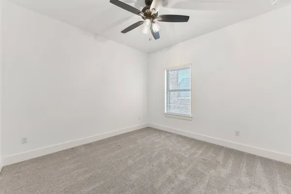 an empty room with windows and ceiling fan