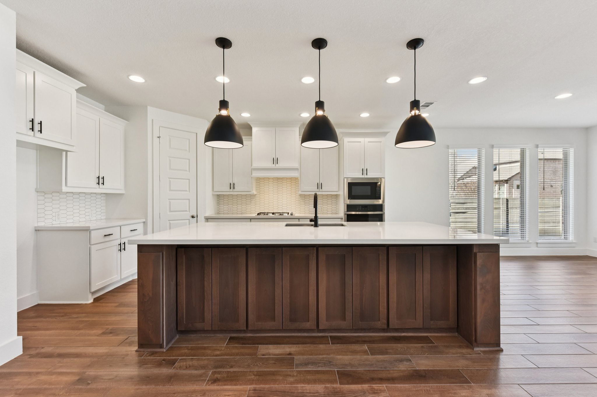 225 Ashmore Lane Georgetown, TX 78628 - Photo 4 of 36 What a gorgeous kitchen - crisp white cabinets with black accent pulls and custom black pendant lighting. Topped off with a center island with stained cabinets with a ton of storage. Custom backsplash tile and walk-in pantry round out the features of this stunning kitchen