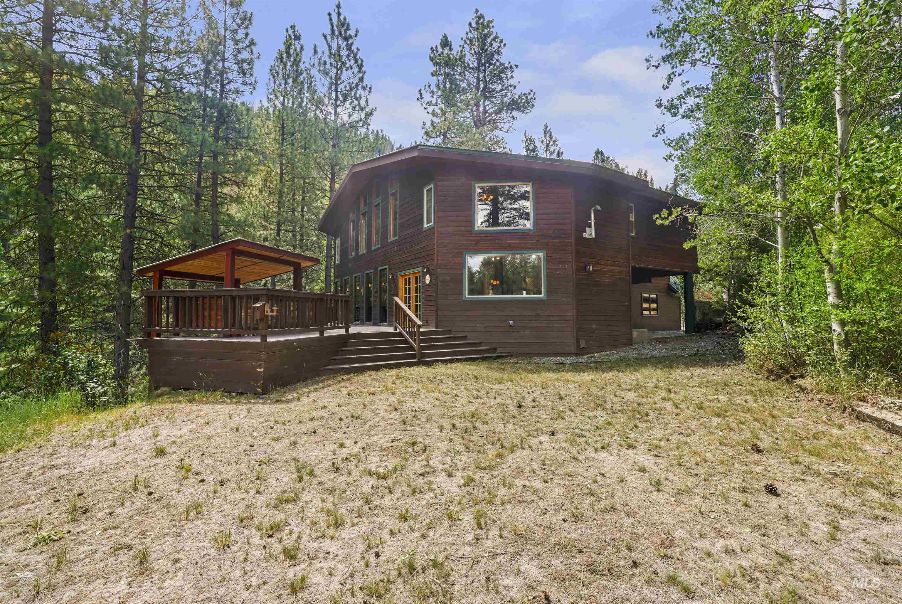 224 Dakota Road Mountain Home, ID 83647 - Photo 37 of 50 Wood-sided exterior featuring an elevated deck with a covered gazebo, multiple large windows, and a surrounding natural environment with mature trees