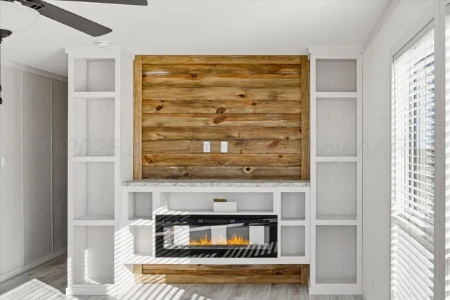 a view of a room with wooden floor ceiling fan window and kitchen view