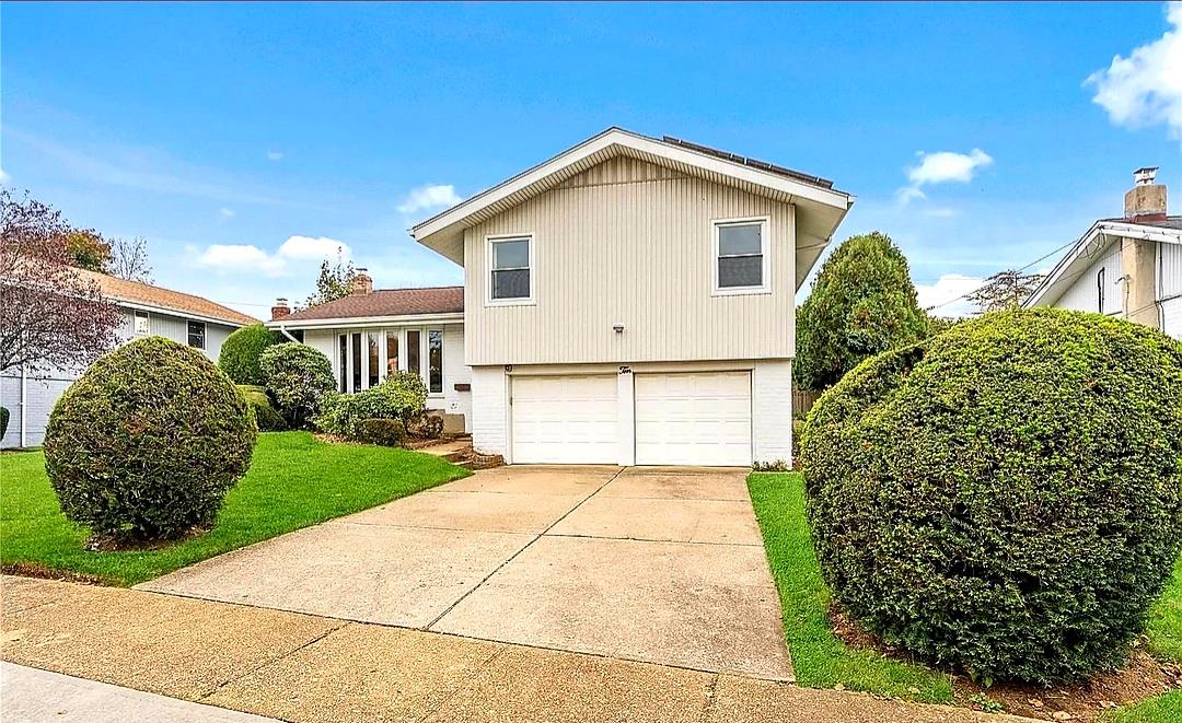 Split level home featuring a garage, a front yard, and driveway