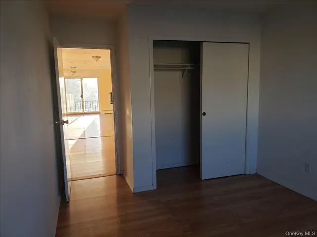 an empty room with wooden floor closet and windows